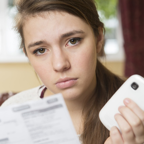 Young woman looking concerned about phone bill