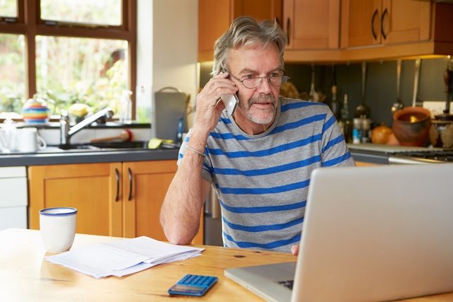Man on telephone sitting in front of laptop